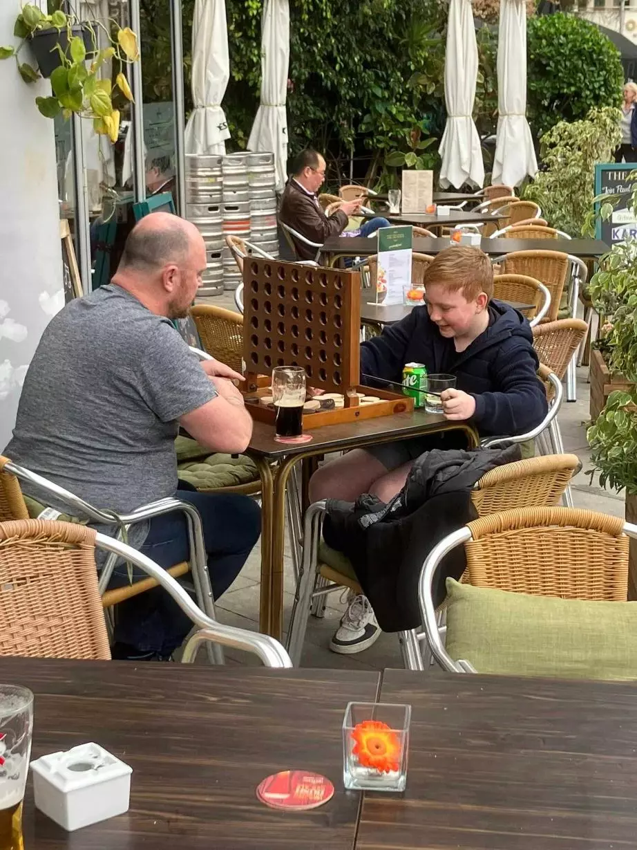 Father and Son playing Connect 4 board game on the terrace